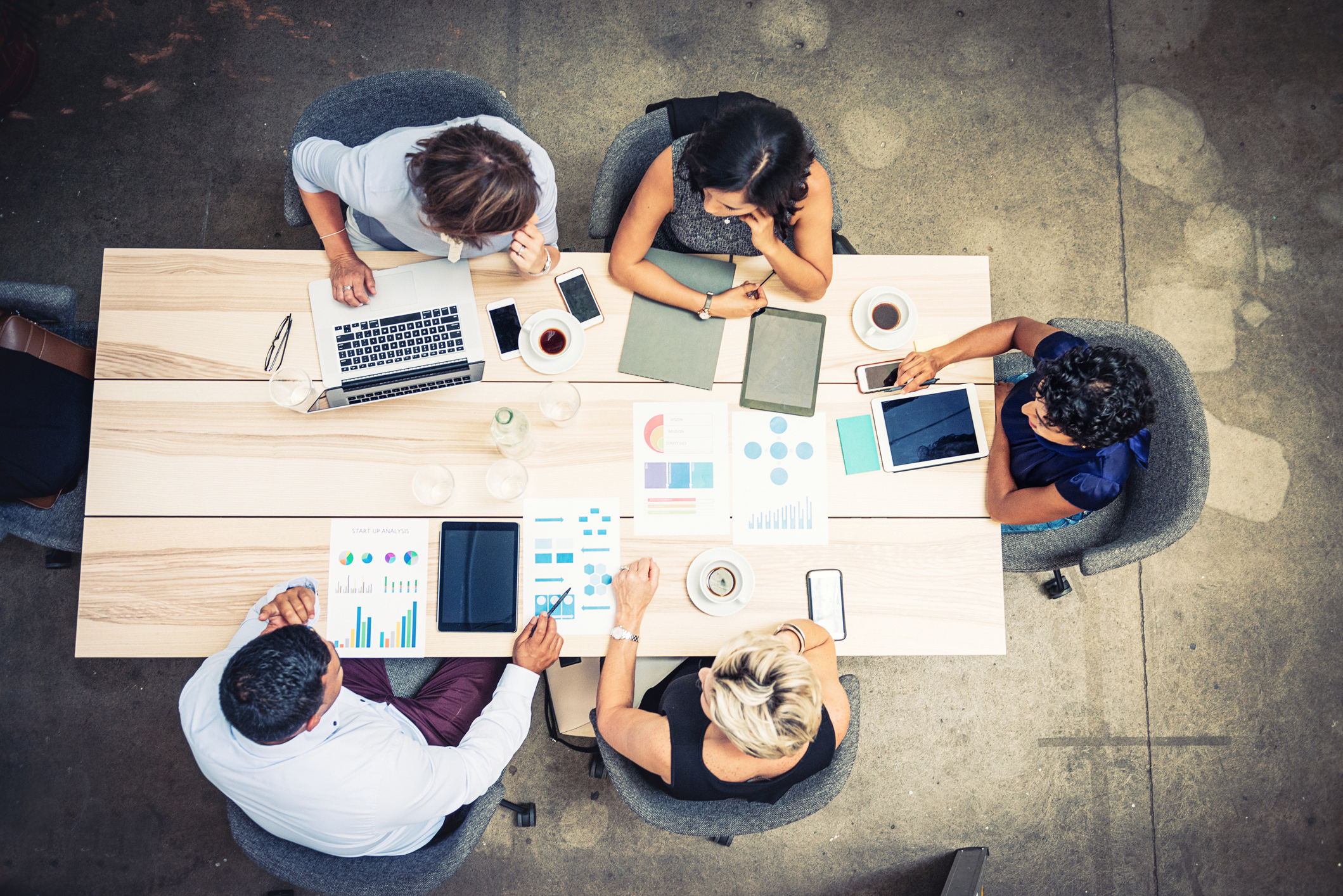 overhead view of five businesspeople examining documents at a conference table