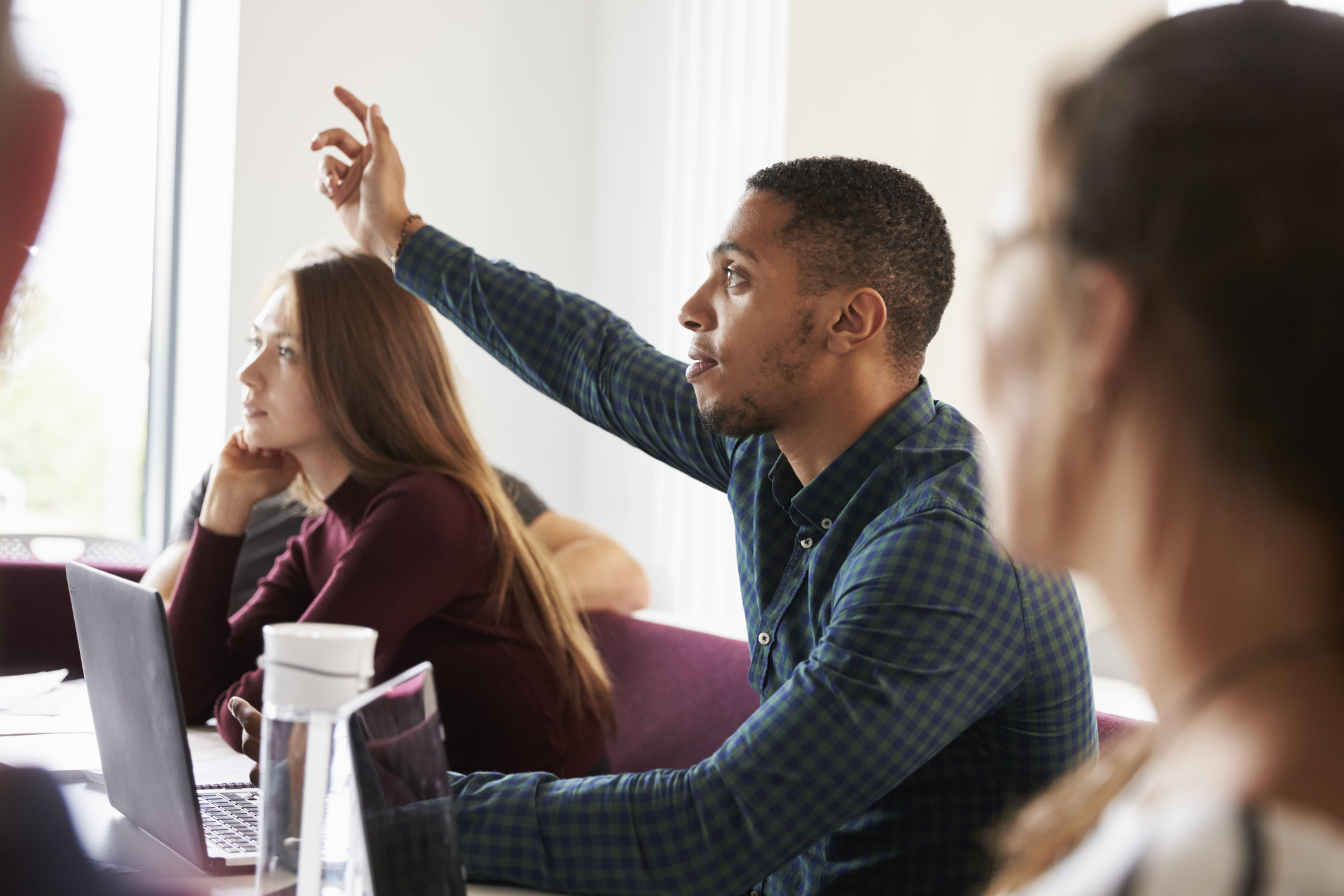 Student raising his hand in a university lecture hall