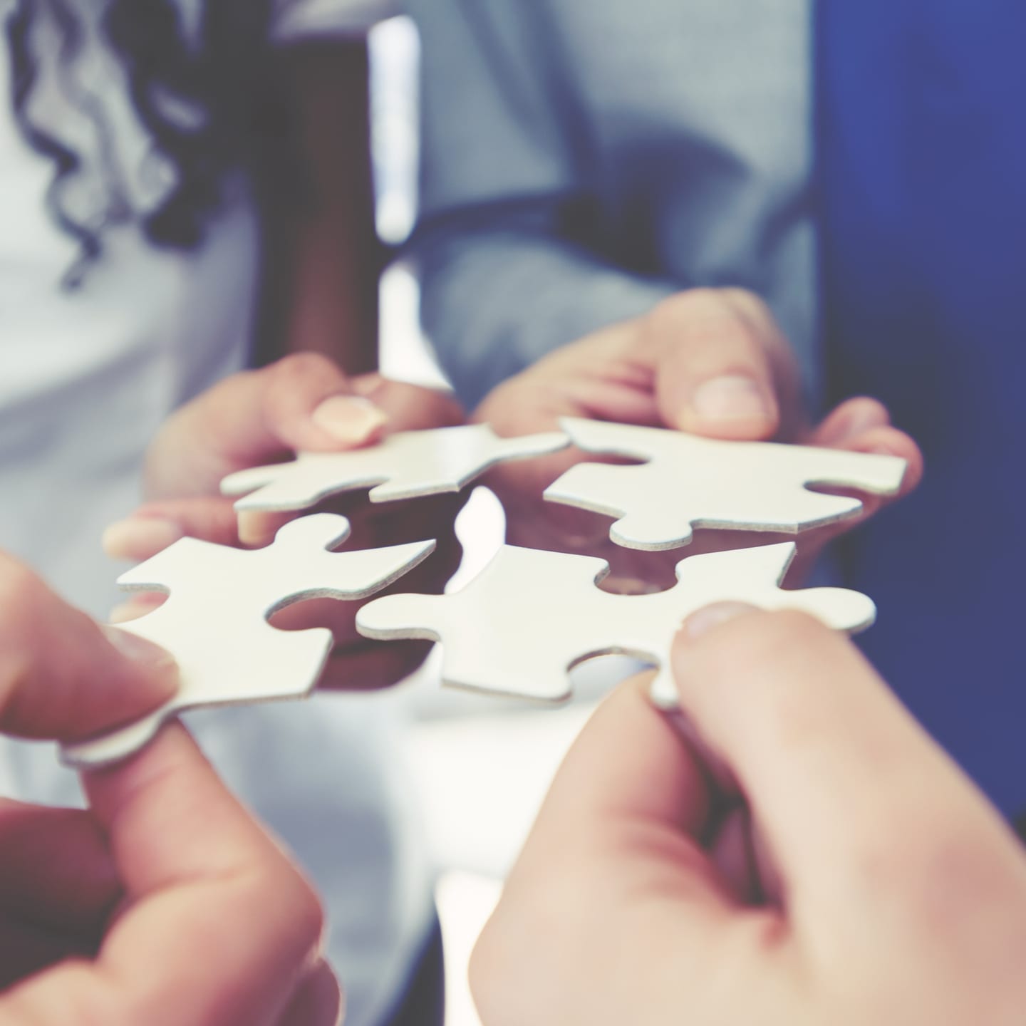 group of people holding puzzle pieces together