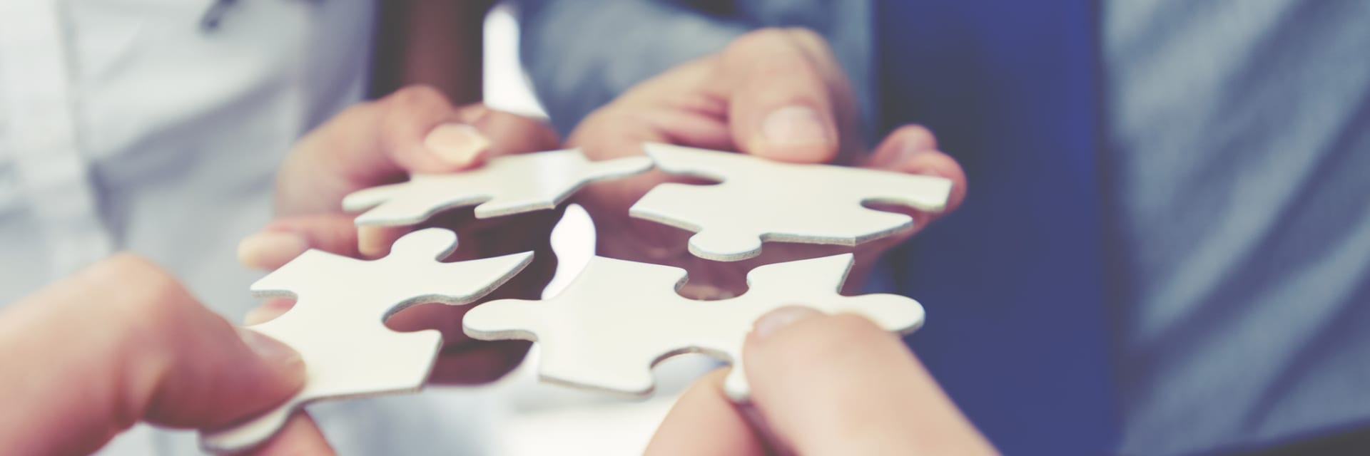 group of people holding puzzle pieces together