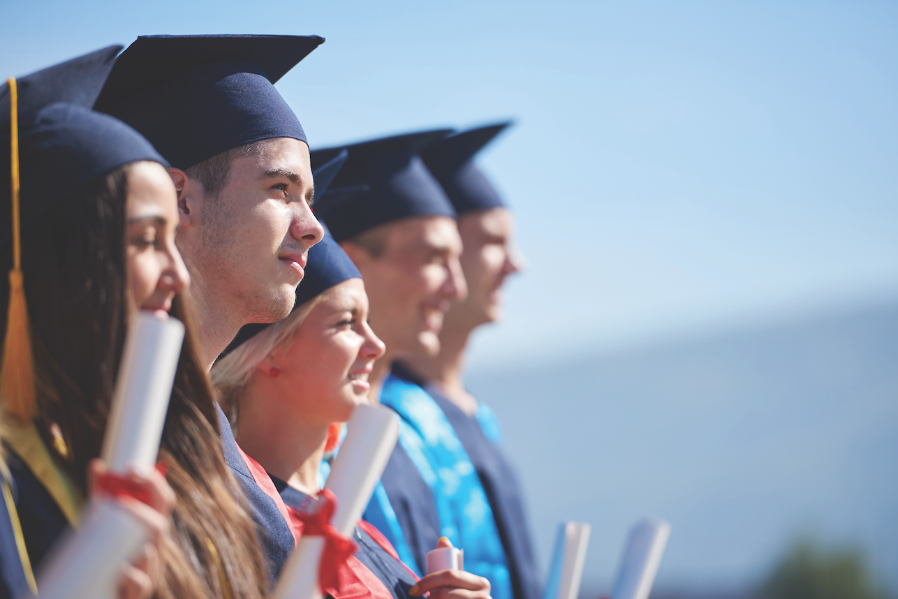 Line of students in mortarboards with diplomas graduating